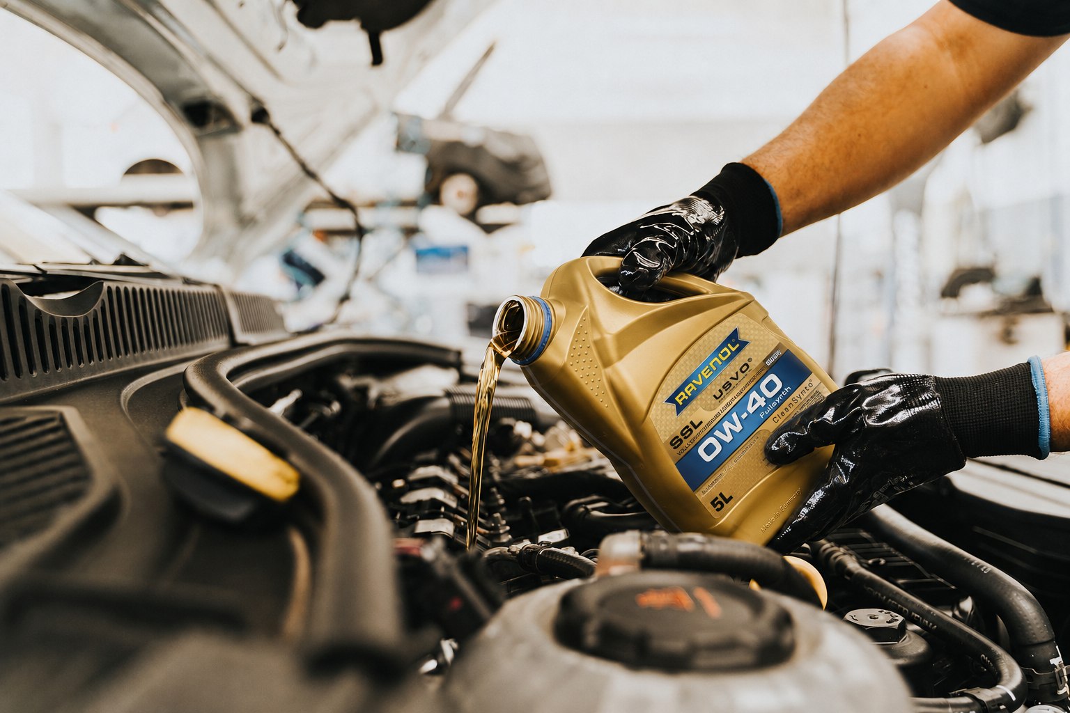 Mechanic pouring Ravenol motor oil into a car engine